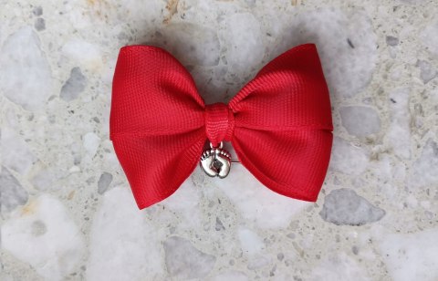 Czerwona kokardka na agrafce ze stópkami do wózka
